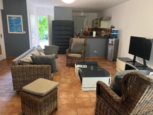 a living room with couches and chairs and a tv at ocean view, on the beach. in Le Gosier