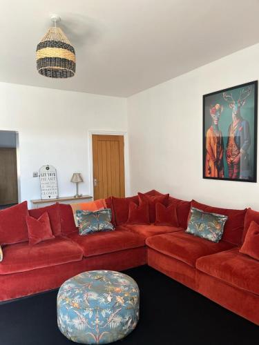 ein Wohnzimmer mit einem roten Sofa und einem Hocker in der Unterkunft The Follonsby Foal in West Boldon