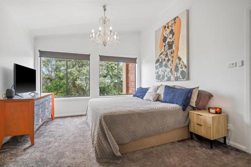 ein Schlafzimmer mit einem Bett, einem Fernseher und einem Fenster in der Unterkunft 27 Burrawong Drive in Port Macquarie