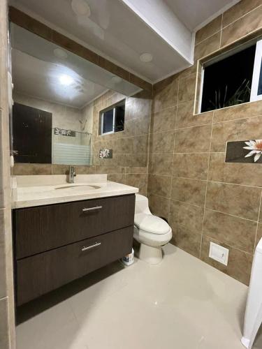 a bathroom with a toilet and a sink and a mirror at Casa Almendra in Melgar