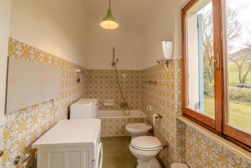 a bathroom with a toilet and a sink and a window at Cà CASTIGLIONE in Acqualagna