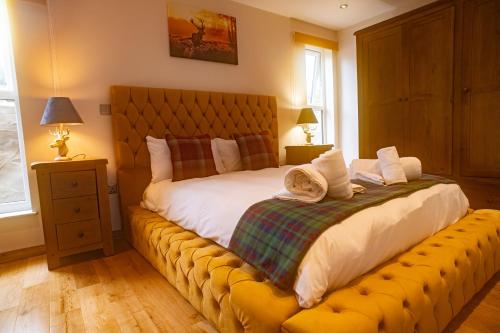 a bedroom with a large bed with a yellow bench at Schoolhouse 1 Cottage by Fairy Pool in Carbost