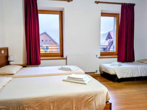 two beds in a room with two windows at La casa del popolo in Prato Carnico
