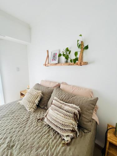 a bed with pillows and a shelf on the wall at Departamento Las Marias in Olavarría