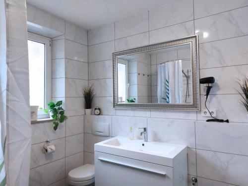 ein weißes Badezimmer mit Waschbecken und Spiegel in der Unterkunft Platz für Gruppen - 4 Schlafzimmer mit TV in Ulm