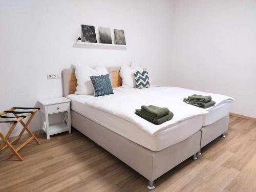 ein weißes Bett in einem Zimmer mit Holzboden in der Unterkunft Platz für Gruppen - 4 Schlafzimmer mit TV in Ulm