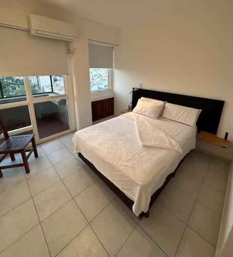 a bedroom with a white bed and a chair at Departamento Resistencia Centro in Resistencia