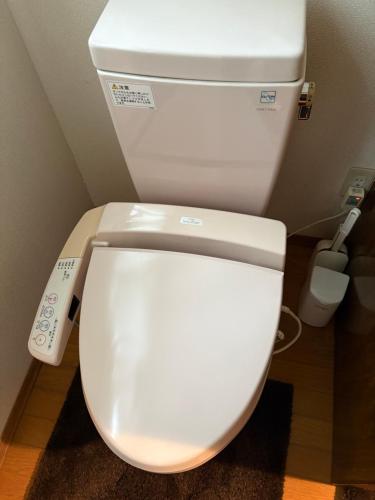 a white toilet with a remote control next to it at 蔵王ペンション kobaya in Kaminoyama