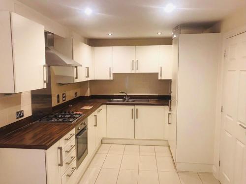 eine weiße Küche mit weißen Schränken und einer Spüle in der Unterkunft Royal Brick Home - Sleeps 5 to 6 - No ULEZ - Tube Nearby - Free Parking - Lego Themed in Slough