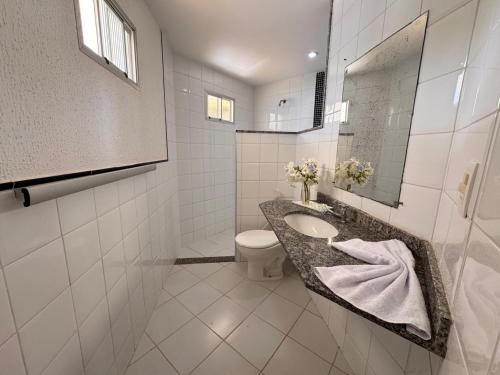 Un baño con lavabo, inodoro y espejo. en Pousada Tabatinga, en Conde