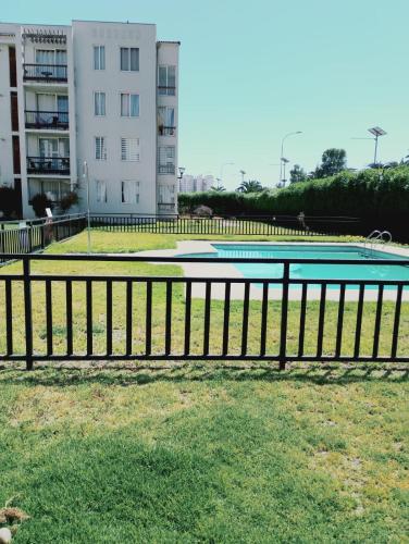 a swimming pool with a fence next to a building at Cómodo y espacioso departamento en La Serena in La Serena