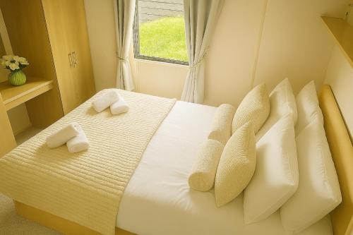 阿伯里斯特威斯Welsh Seaview Stay 3 bed caravan by pool, club and beach的一间卧室，配有一张带白色枕头的床和一扇窗户
