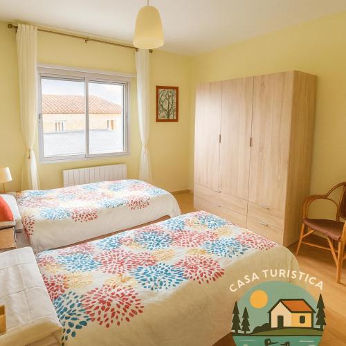 a bedroom with two beds and a cabinet and a window at La Balsa in Matalebreras