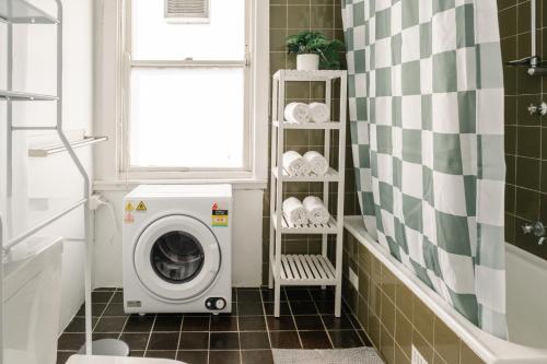 a washing machine in a bathroom with a window at Chic 2BR Terrace w City and Harbour Bridge Views in Sydney
