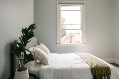 a white bedroom with a bed and a window at Chic 2BR Terrace w City and Harbour Bridge Views in Sydney