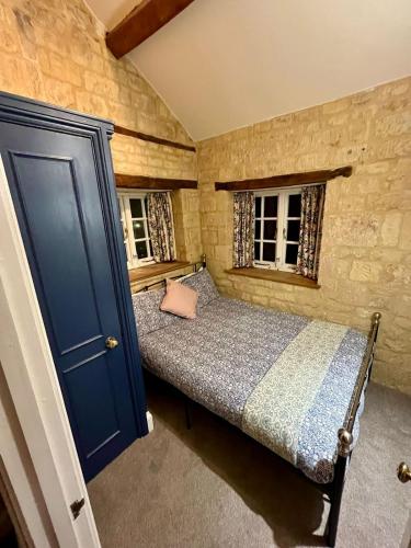 a small bedroom with a bed and two windows at The Carriage House in Blockley
