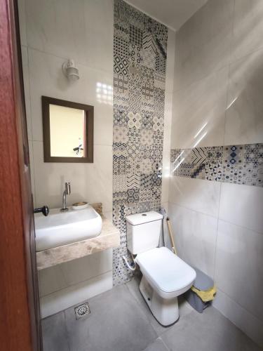 ein Badezimmer mit einer weißen Toilette und einem Waschbecken in der Unterkunft Casa Mahalo - no centro de Cumbuco in Caucaia