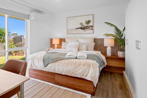 a bedroom with a bed with two towels on it at Salt & Sky - Luxe Coastal Getaway in Coffs Harbour