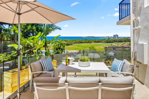 eine Terrasse mit Tisch und Stühlen und einem Sonnenschirm in der Unterkunft Salt & Sky - Luxe Coastal Getaway in Coffs Harbour