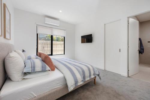 Una habitación blanca con una cama y una ventana en Peninsula Sea Breeze, en Safety Beach