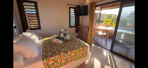 Un dormitorio con una cama y un balcón con una mesa. en Revatua Lodge - Piscine privée et Petit-déjeuner inclus, 