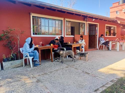 een groep mensen aan een tafel met twee honden bij Playa Hostel in Santa Rosa de Calamuchita