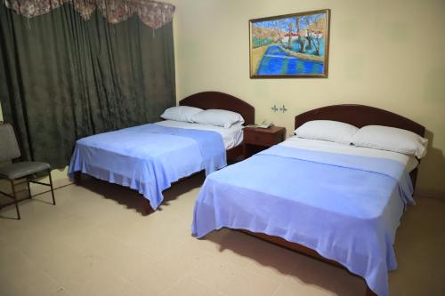 ラス・タブラスにあるvilla Tableñaのベッドルーム1室(ベッド2台、椅子、絵画付)