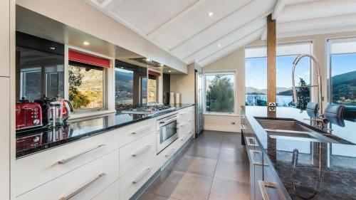 a kitchen with white cabinets and large windows at Stewart Lodge Luxury Spa in Queenstown
