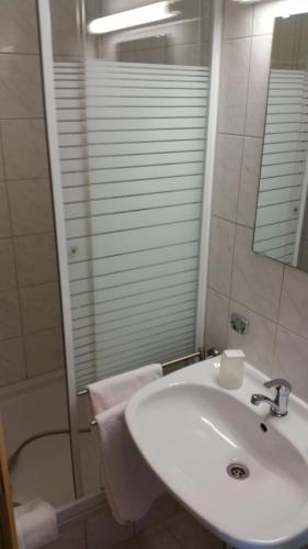 a white bathroom with a sink and a shower at Hotel Elsenztal in Bammental