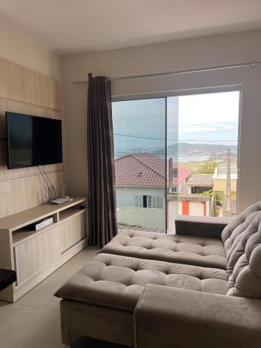 a living room with a large couch and a large window at Casa com vista para o mar e perto do centro in Imbituba
