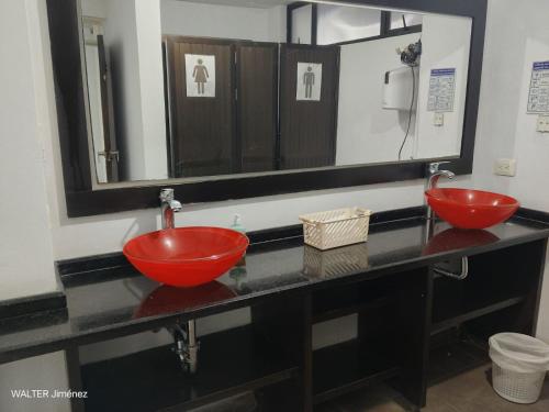 une salle de bain avec deux lavabos rouges et un miroir dans l'établissement Gran Hotel Coral, à Popayan
