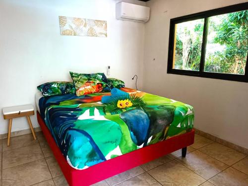 a colorful bed in a room with a window at Vacation house in Tahiti in Punaauia