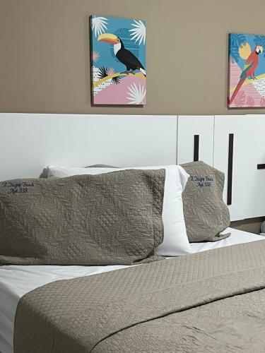 a bed with two pictures on the wall above it at Ponta Negra Beach Melo Flat in Natal