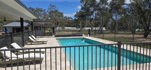 a swimming pool with chairs and a fence at Hideaway In Hartley in Hartley