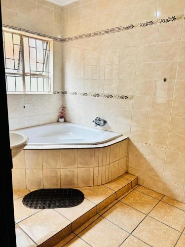 a bathroom with a bath tub and a window at BTV Villa in Hazyview