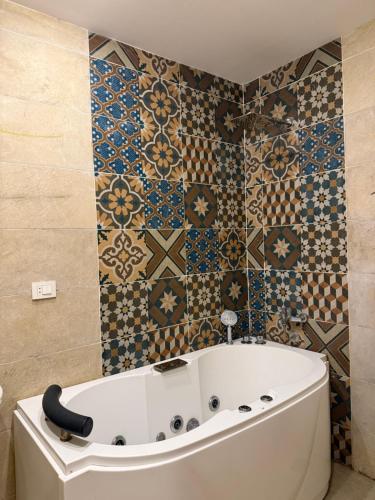 un bagno con vasca e piastrelle sul muro di Aida of pyramids view hotel a Il Cairo