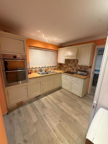 an empty kitchen with white cabinets and a sink at A lovely bungalow with 3 bedrooms and nice garden in Boultham
