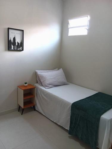 a small bedroom with a bed and a night stand at Natal em Garanhuns, PE - Apartamento minimalista próximo ao Centro in Garanhuns