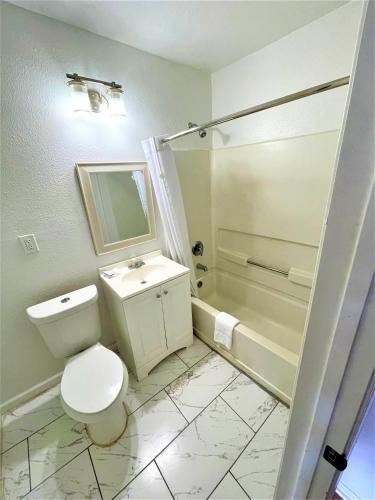a bathroom with a toilet and a sink and a tub at Budget Inn Giddings in Giddings