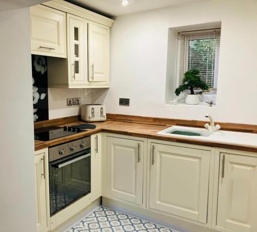 a kitchen with white cabinets and a sink at Nant caer Efail Cottage - Stream by the forge in Pen-y-cae