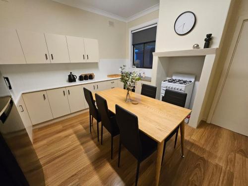 a kitchen with a table and chairs and a clock on the wall at Neat & Tidy Family Home with Beautiful Back Yard in Angaston