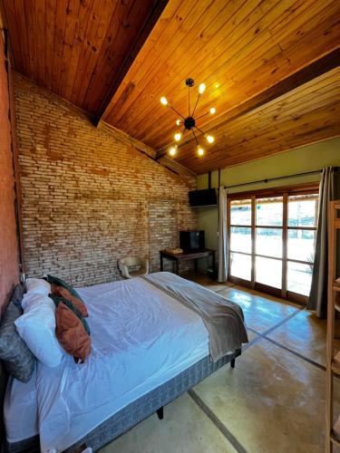 a bed in a room with a brick wall at Sítio Santo Antonio - Chalé 02 com Ofurô in Jarinu