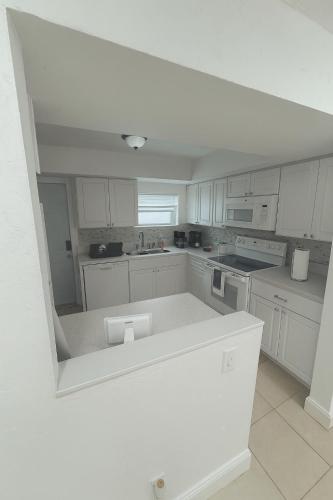 a kitchen with white cabinets and a white counter top at Pacifica Fort Lauderdale Airport in Dania Beach