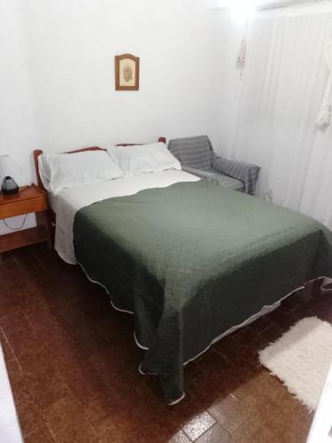 a bedroom with a bed with a green blanket and a chair at Departemento Garay in San Bernardo