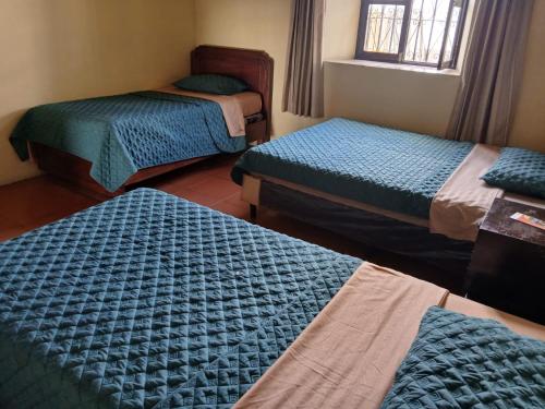 a room with three beds and a window at Jardín de Los Sueños Quinta San Felipe in Antigua Guatemala
