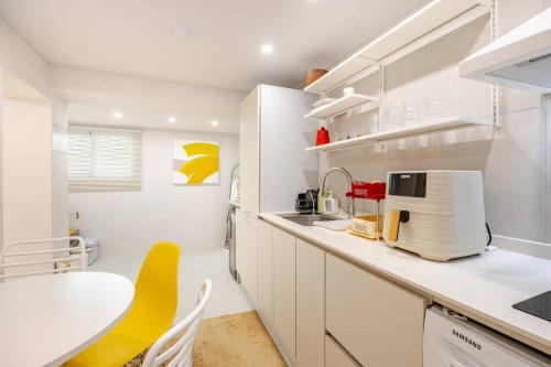 eine weiße Küche mit einem Tisch und einem gelben Stuhl in der Unterkunft 서울 성북 D'enough House in Seoul