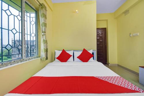 Un dormitorio con una cama con almohadas rojas y una ventana. en Hotel O Maa Residency Near Biswa Bangla, en Thākurdwari