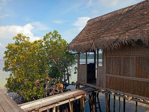 MinyaifuinにあるSeawhip Homestayの水上に建つ茅葺き屋根の建物