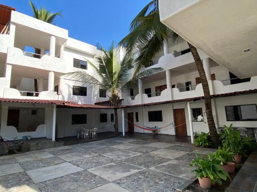 a large white building with a courtyard with palm trees at Costa Ayala - Bungalow 1 with 2 dbl beds and 2 sofas in Los Ayala