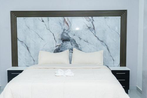 un grand lit blanc avec une tête de lit en marbre dans l'établissement Deramai, à Santo Domingo de los Colorados
